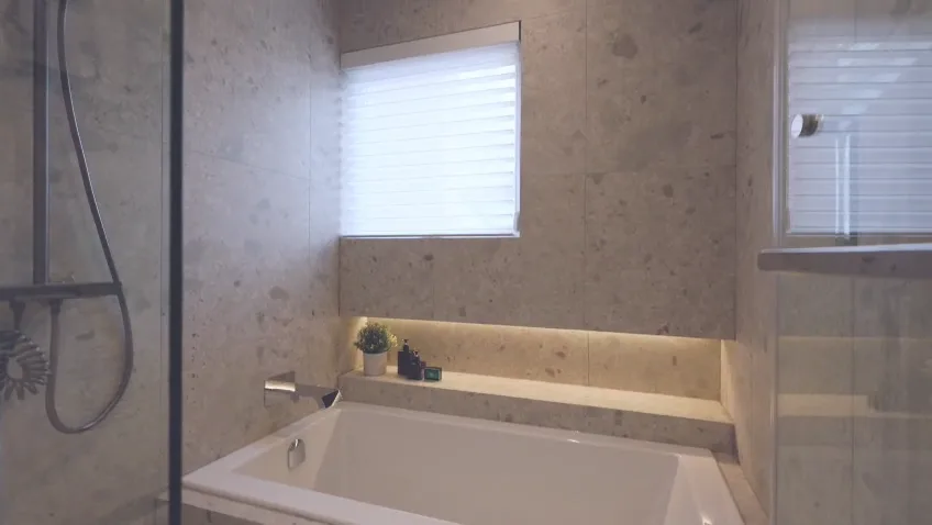 Stone bathroom with an LED-lit shelf niche in a custom home