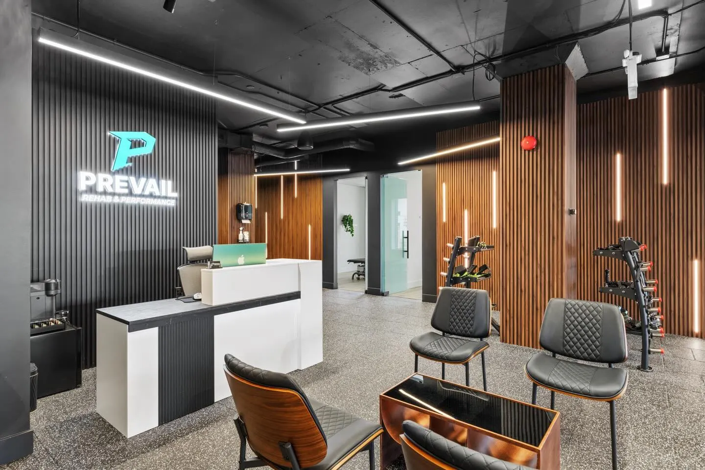 Reception and waiting area with backlit logo wall and slat-wall accent lighting at Prevail Rehab, Toronto